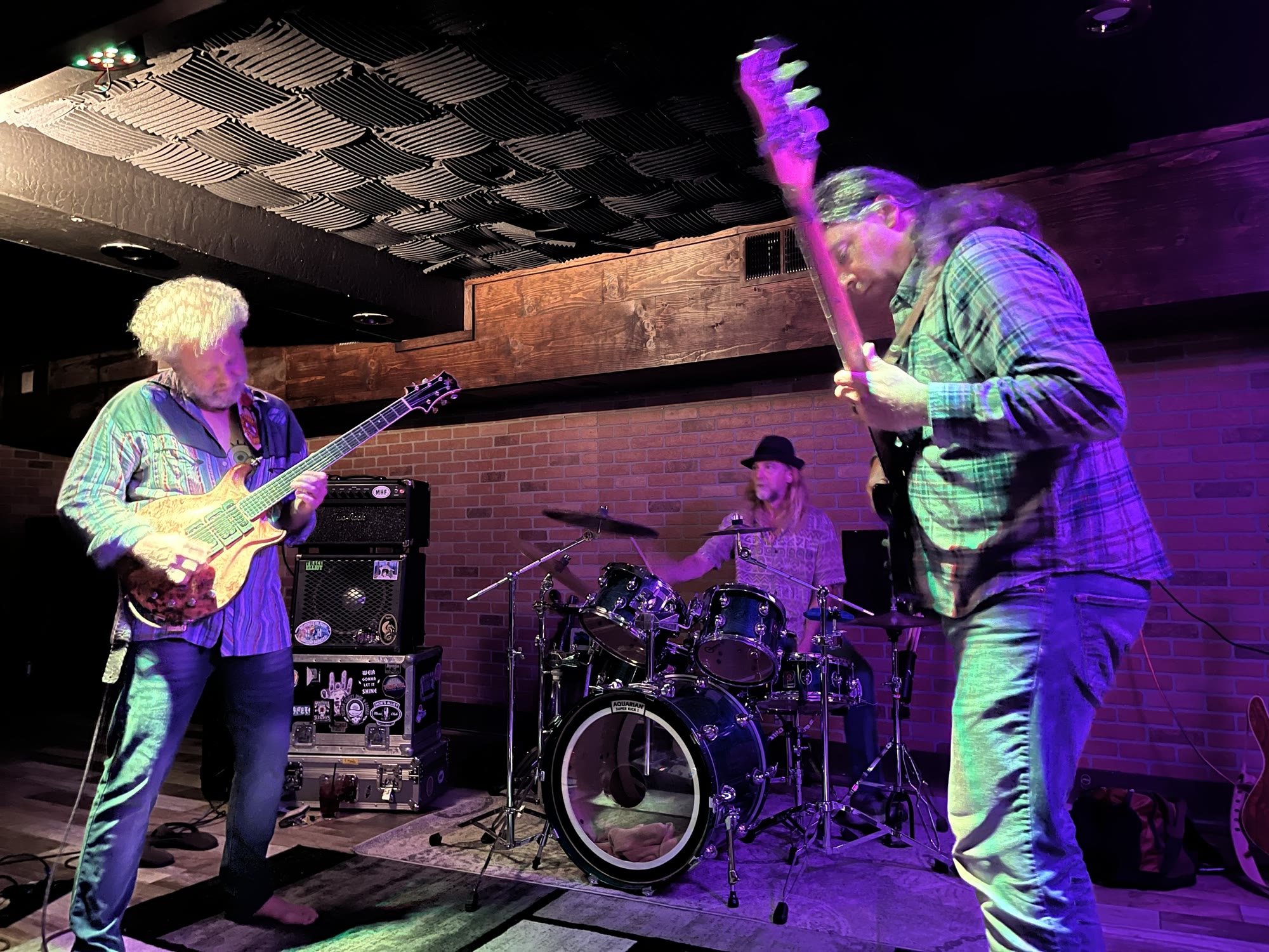 Slingshot Improv Trio playing live under purple and green stage lights